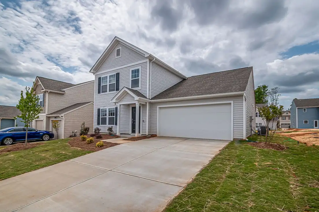 A builder-grade suburban house with a white two-car garage door facing the street
