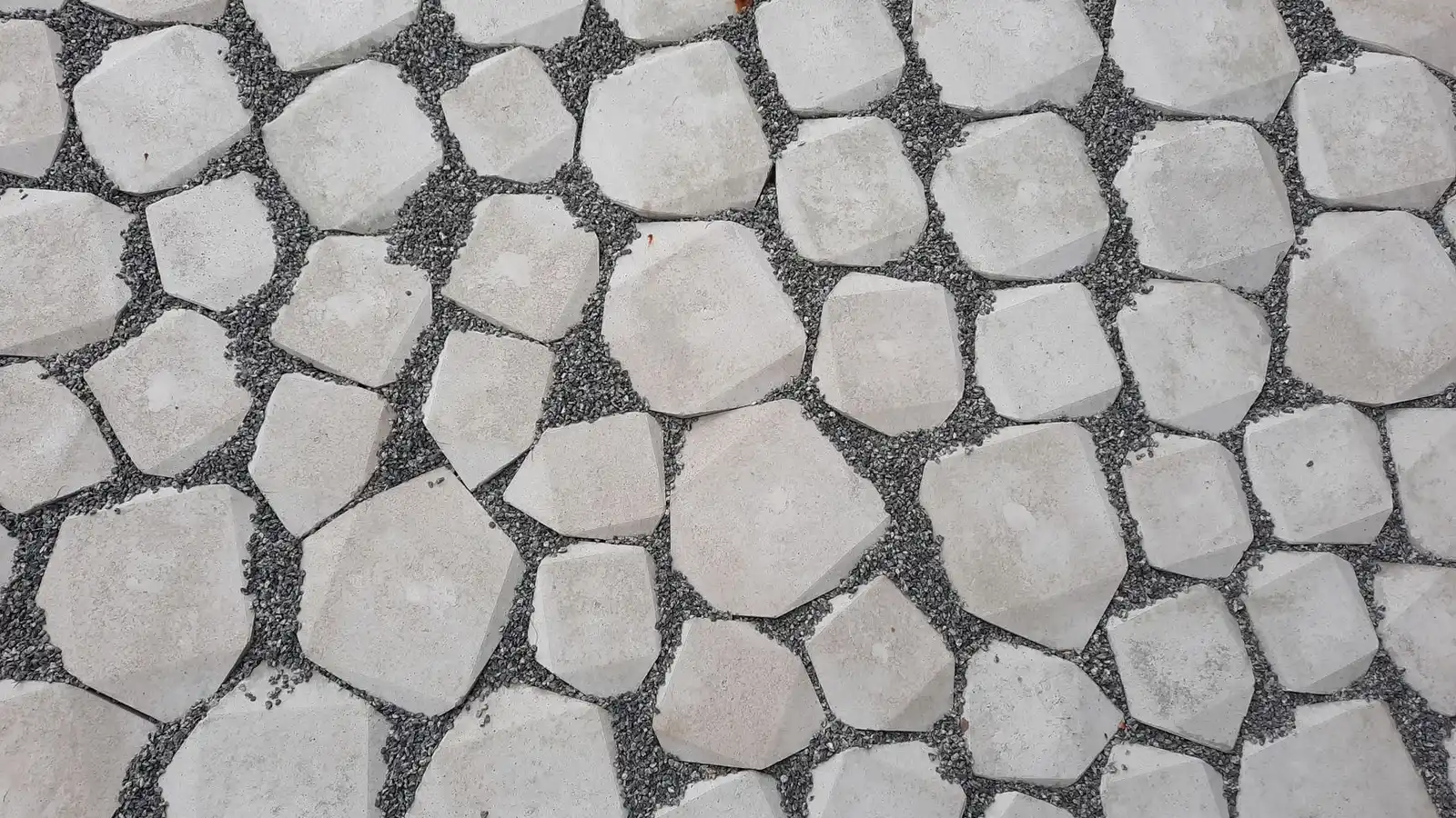 Irregular concrete pavers set into pea gravel forming a garden patio surface