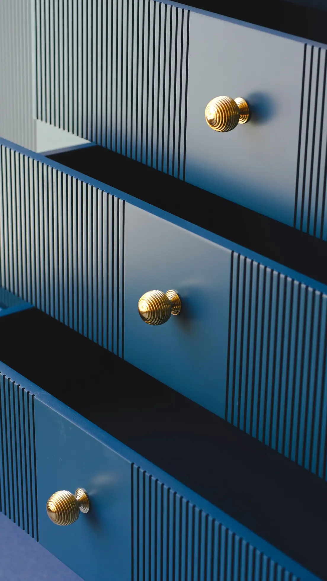 Close-up of brass knobs on blue dresser drawers
