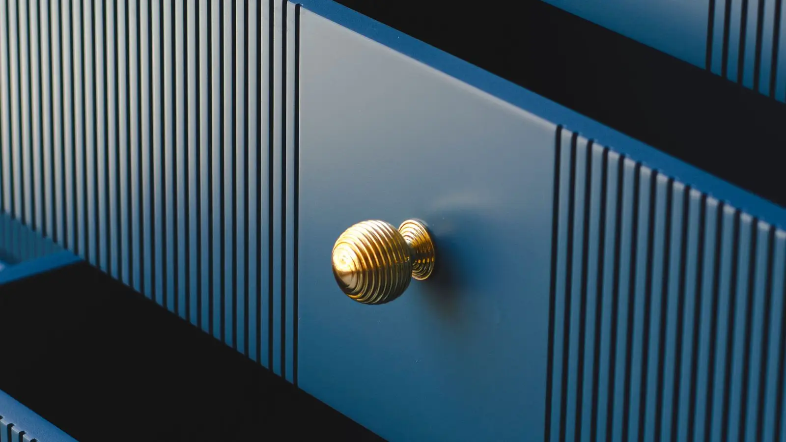 Close-up of brass knobs on blue dresser drawers