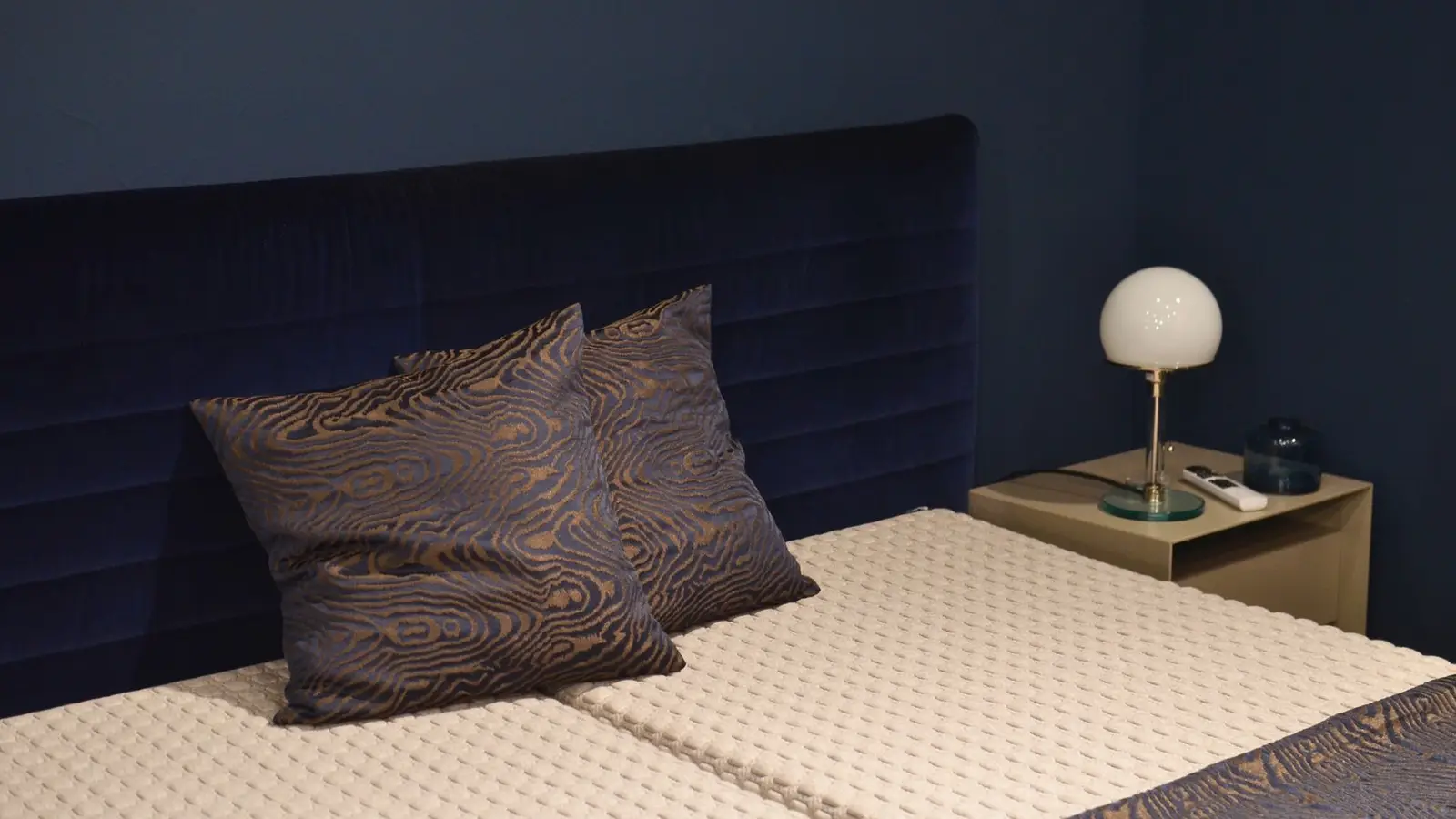 A navy upholstered headboard blending into a matching navy bedroom wall