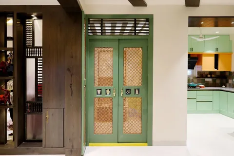 A green paneled door opening into a closed kitchen with pastel green cabinetry