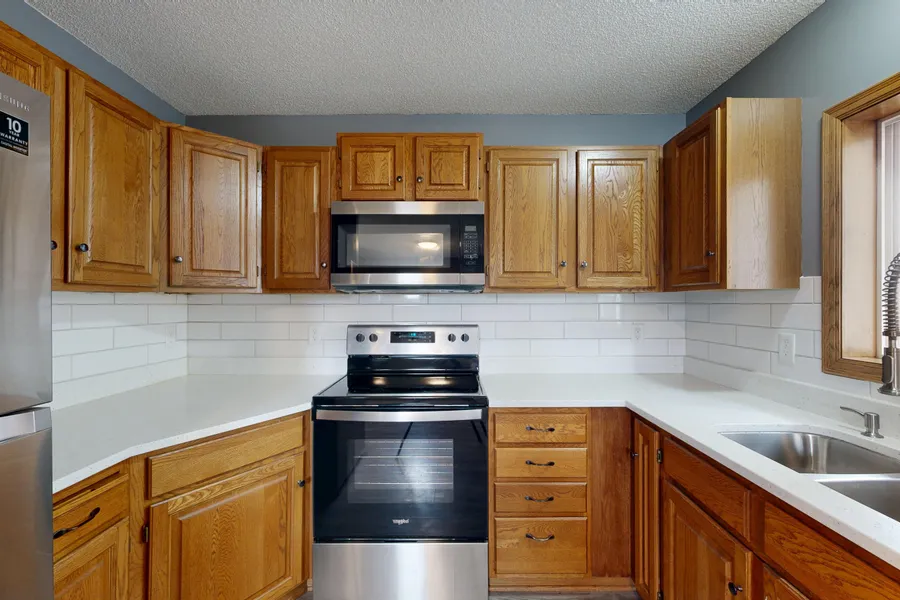 A kitchen with a white subway tile backsplash installed above the counter and stove