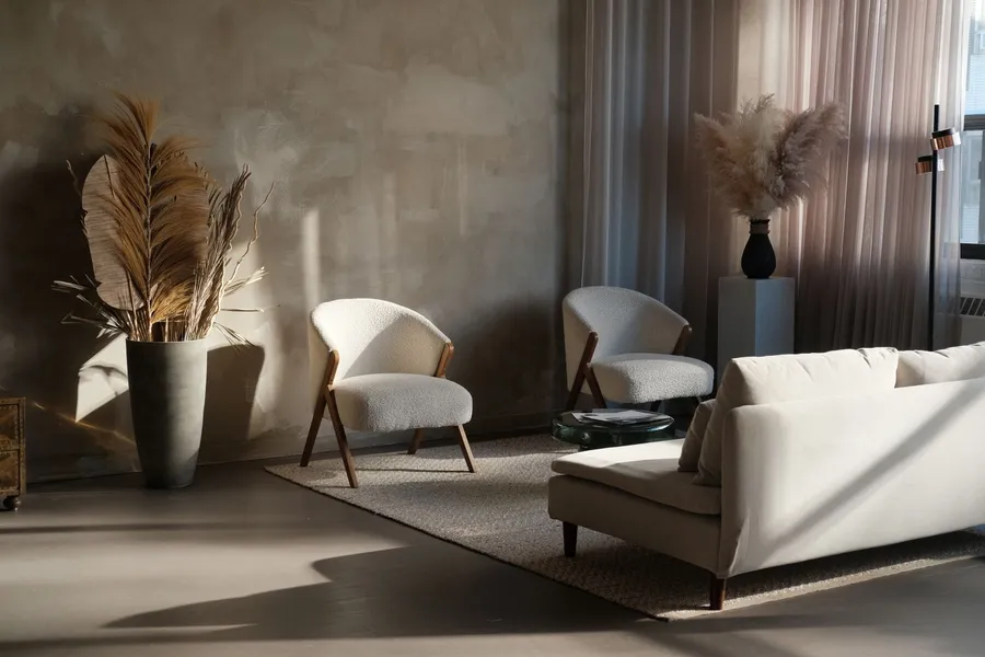A moody japandi living room with dried pampas grass, boucle armchairs, and warm late-day light