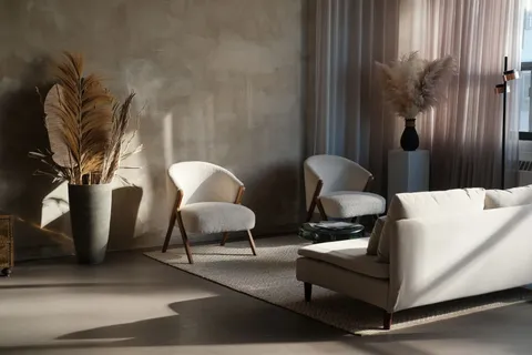 A moody japandi living room with dried pampas grass, boucle armchairs, and warm late-day light