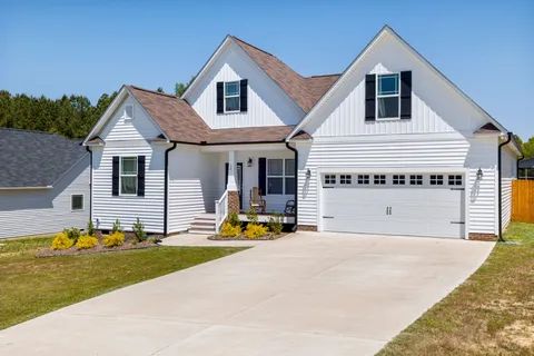 A simple home exterior design with white siding, black shutters, and matching black garage hardware