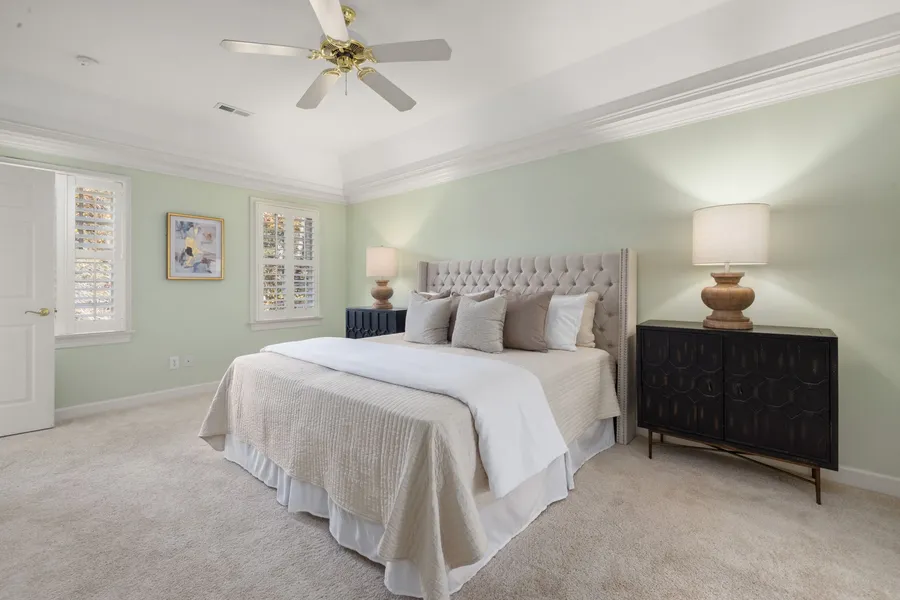 A small primary bedroom with a queen bed centered on the long wall between two matching nightstands and lamps