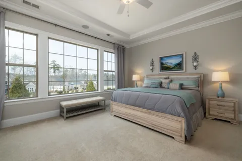 A couples bedroom with a king bed, matching nightstands and lamps on both sides, and a bench at the foot of the bed