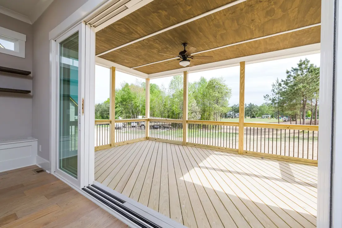 An attached patio cover with a wood plank ceiling and ceiling fan over a new backyard deck