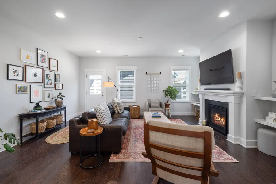 A living room with a wall-mounted TV, colorful gallery wall, and a white fireplace mantel below it