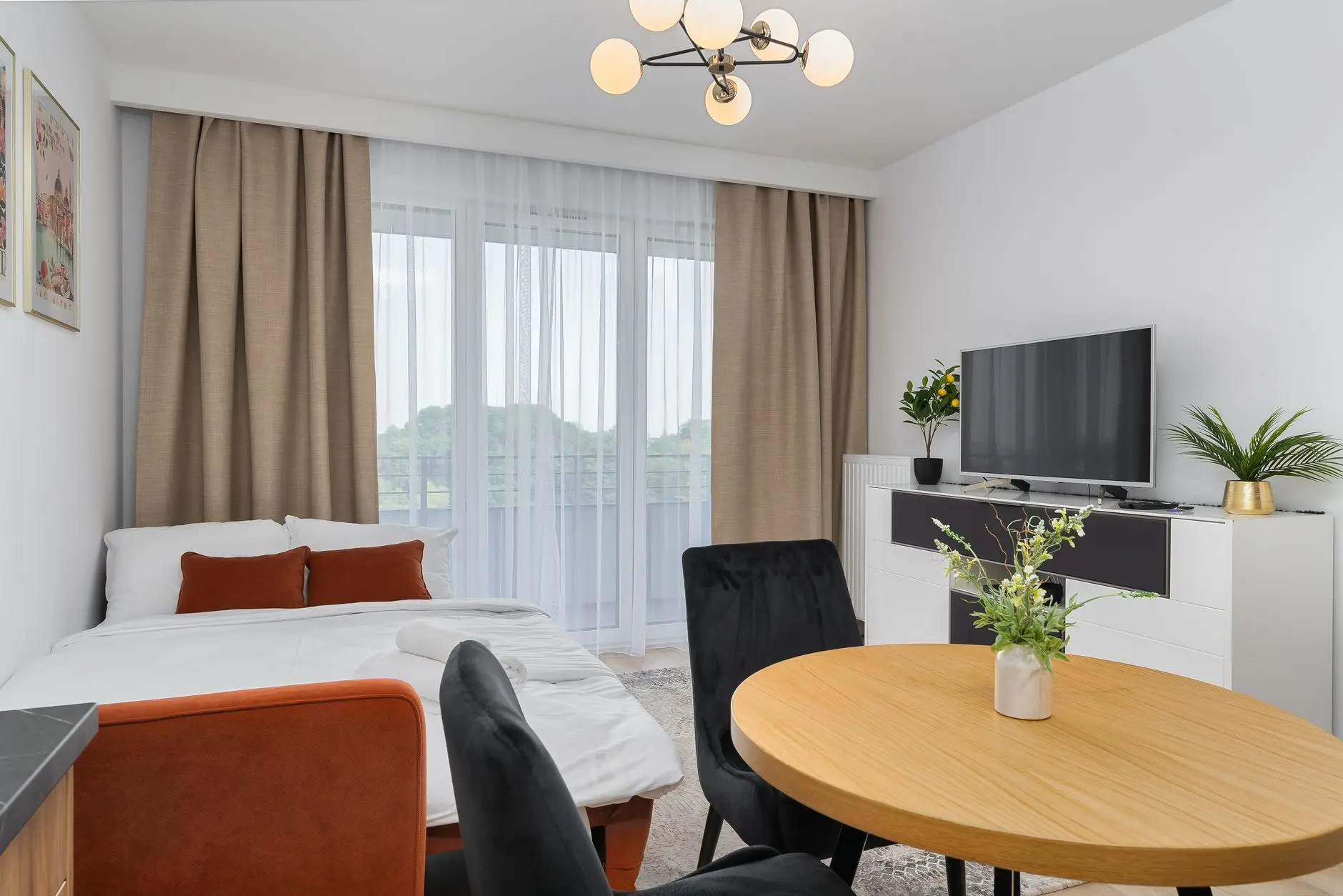 A compact studio apartment with a bed doubling as a sofa and a small round dining table, an example of multifunctional furniture for small apartments