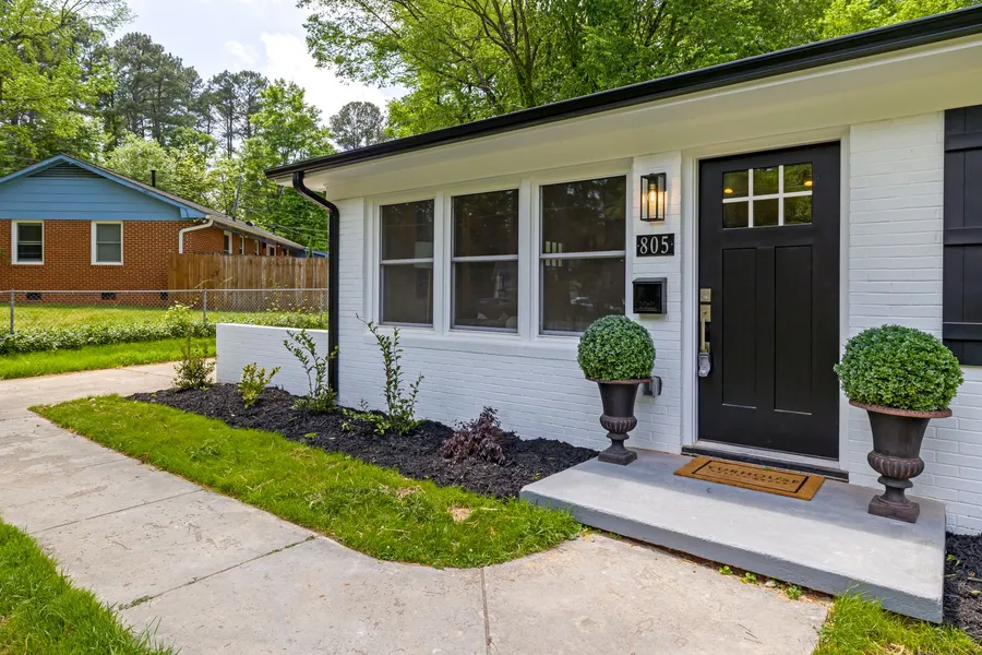 A ranch house with strong curb appeal — a black front door, matching planters, and clear house numbers
