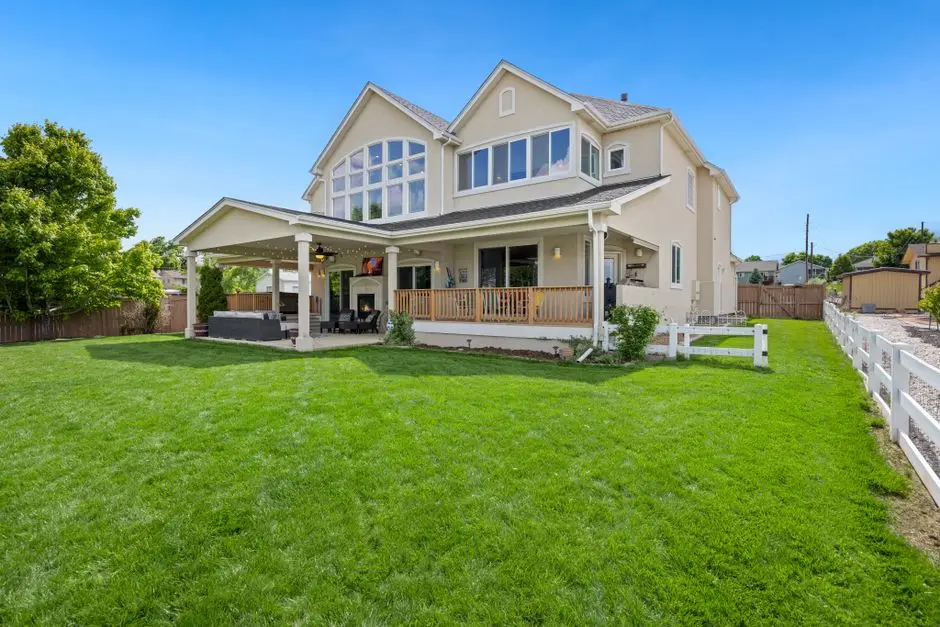A house with a covered, attached porch overlooking a large backyard lawn