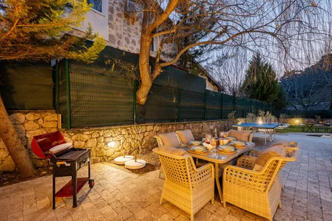 Outdoor dining table and charcoal grill set up in a backyard BBQ area at dusk