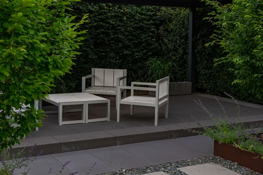 A modern gray paver patio with minimalist wood-and-metal outdoor furniture