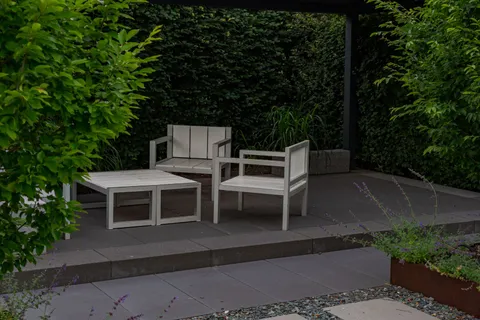 A modern gray paver patio with minimalist wood-and-metal outdoor furniture