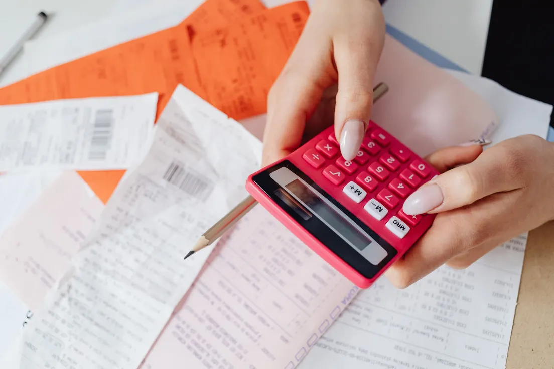 A person using a calculator to add up receipts for a backsplash project budget
