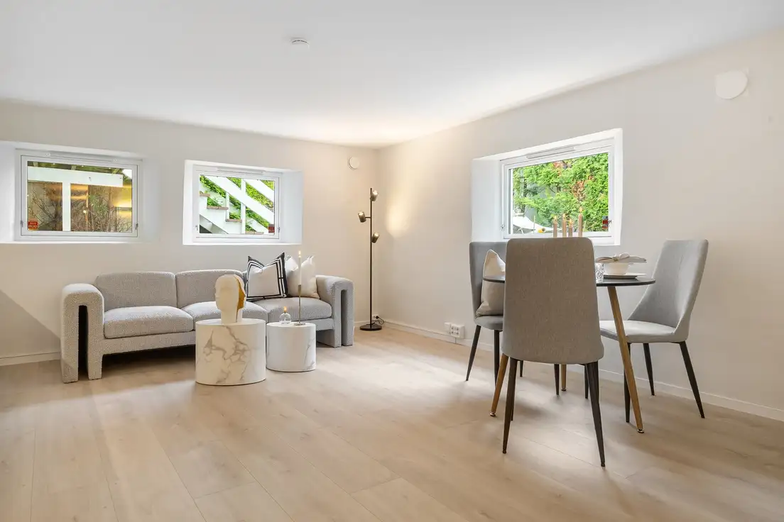 A small living room dining room combo with a gray sofa, marble side tables, and a round dining table with two gray chairs on a budget
