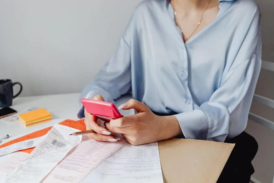 A person using a pink calculator to add up receipts for a home decor budget