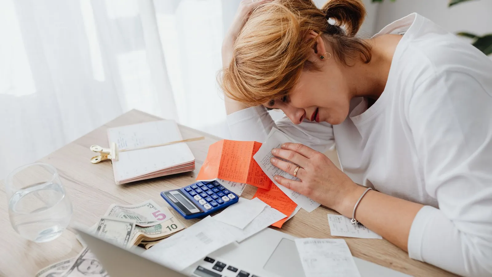 A person calculating a home exterior project budget with receipts and a calculator
