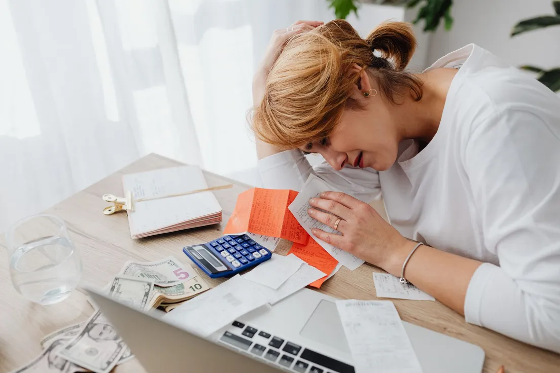 A person calculating a home exterior project budget with receipts and a calculator