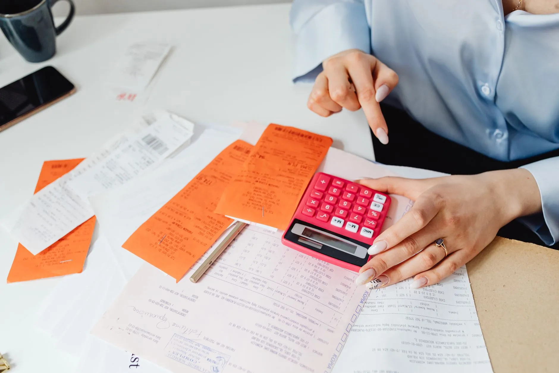 A person adding up a modern farmhouse exterior project budget with receipts and a calculator