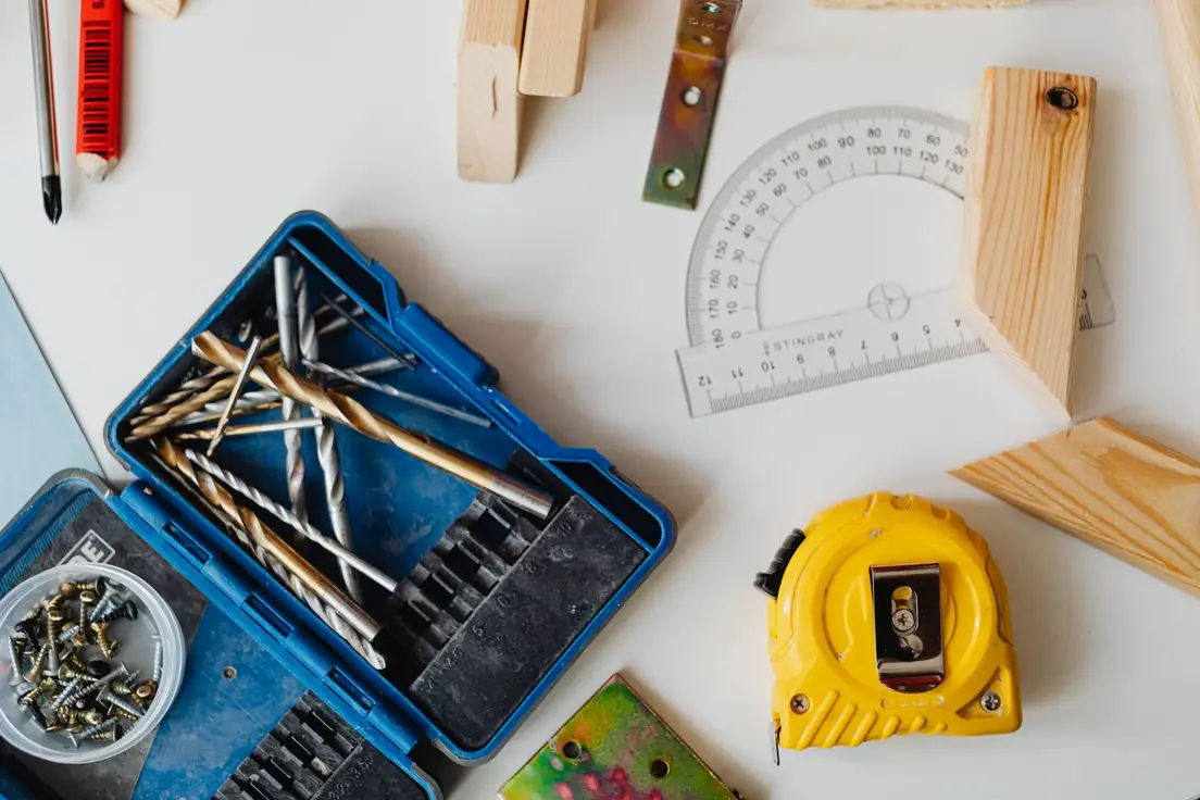 A close-up of a yellow tape measure and protractor among woodworking tools, illustrating the honest math on temporary wall costs