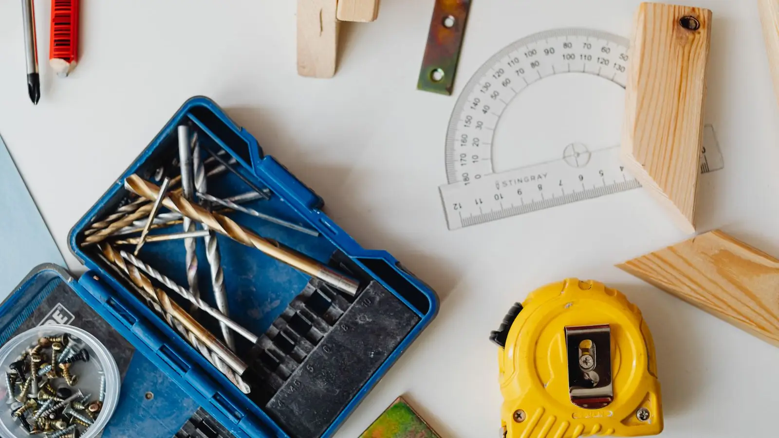 A close-up of a yellow tape measure and protractor among woodworking tools, illustrating the honest math on temporary wall costs
