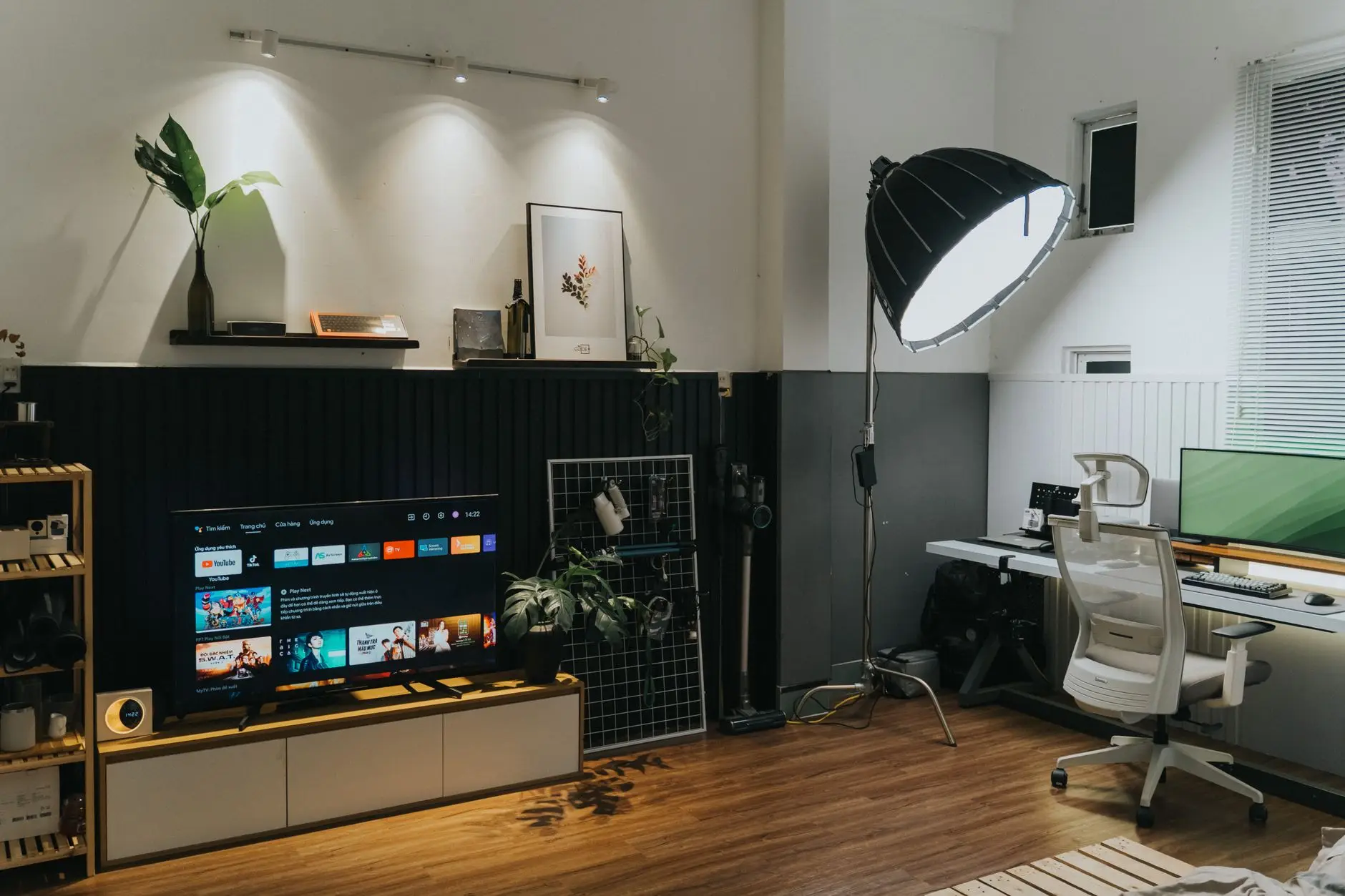 A living room with a TV console on one side and a desk with an office chair on the other, a full living room office setup in one room