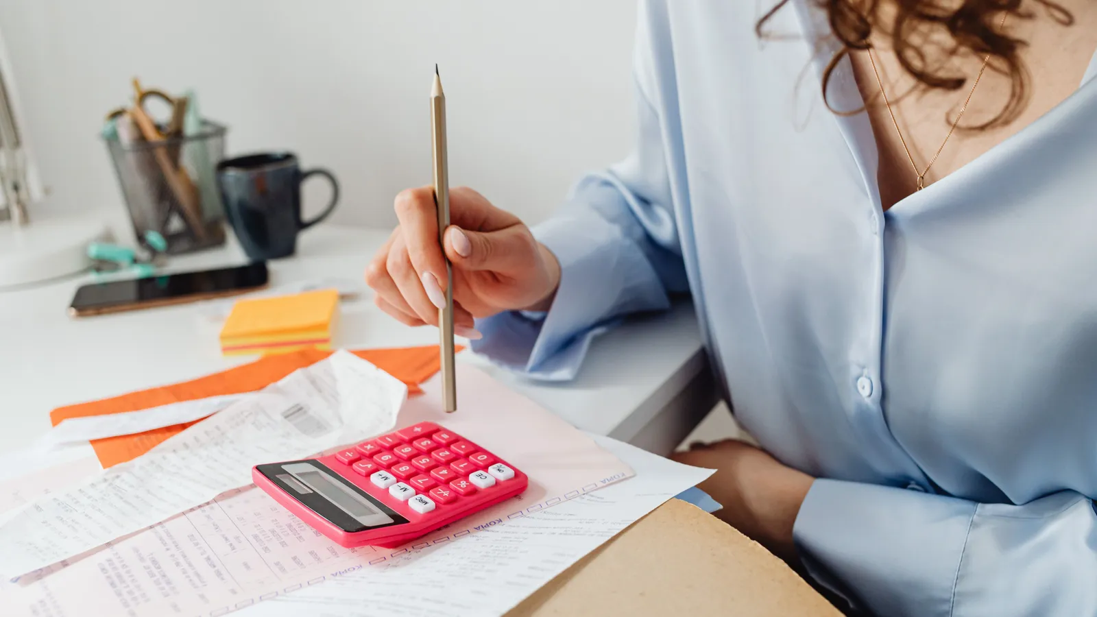 A person using a calculator and pencil to add up a kitchen renovation budget