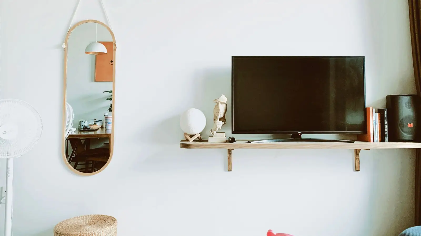 A TV on a floating wood shelf mounted against a plain wall