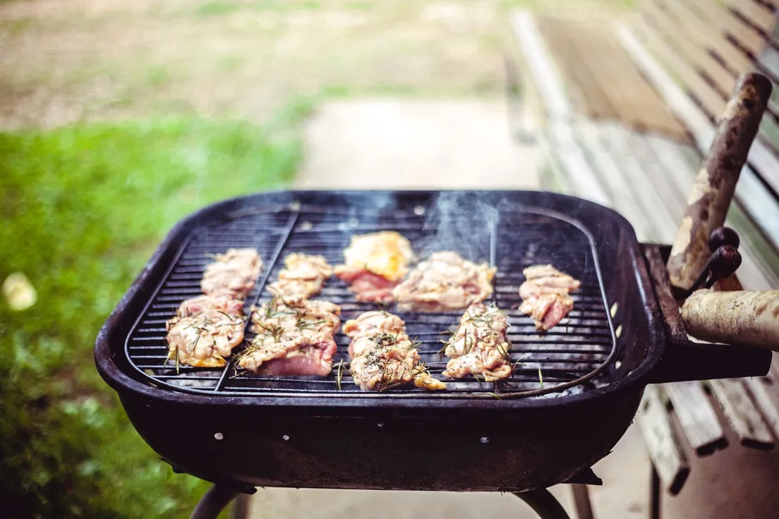 Chicken thighs cooking on a small outdoor grill for a backyard bbq area