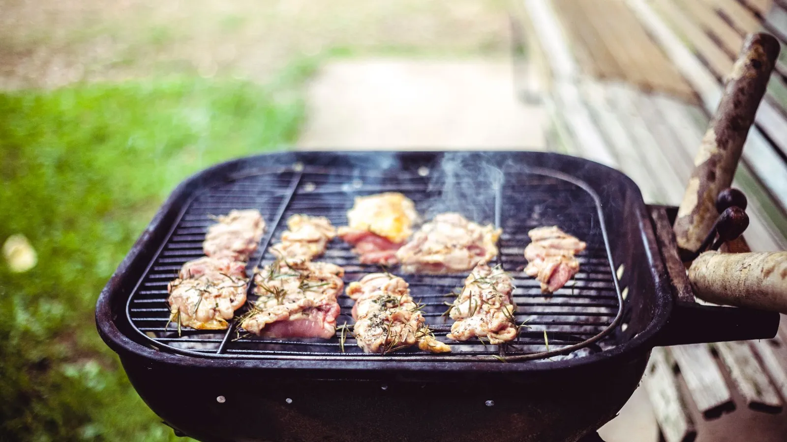 Chicken thighs cooking on a small outdoor grill for a backyard bbq area
