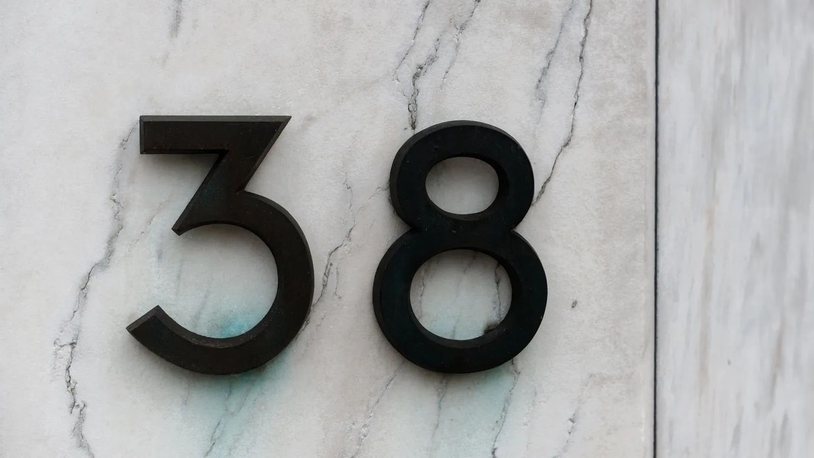 Modern black house numbers mounted on an exterior wall