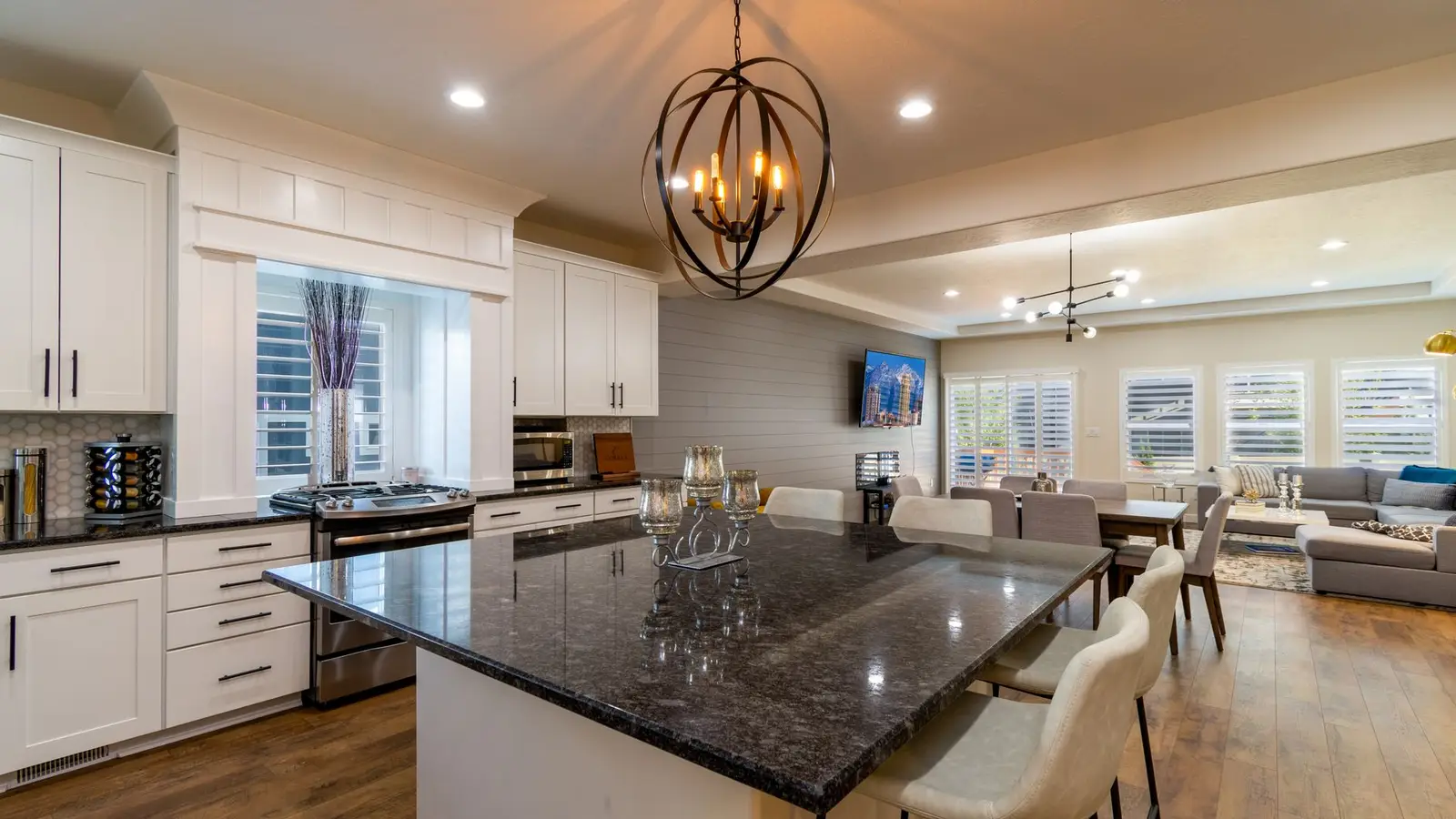 A dark kitchen island with counter stools dividing an open kitchen from the living room seating area