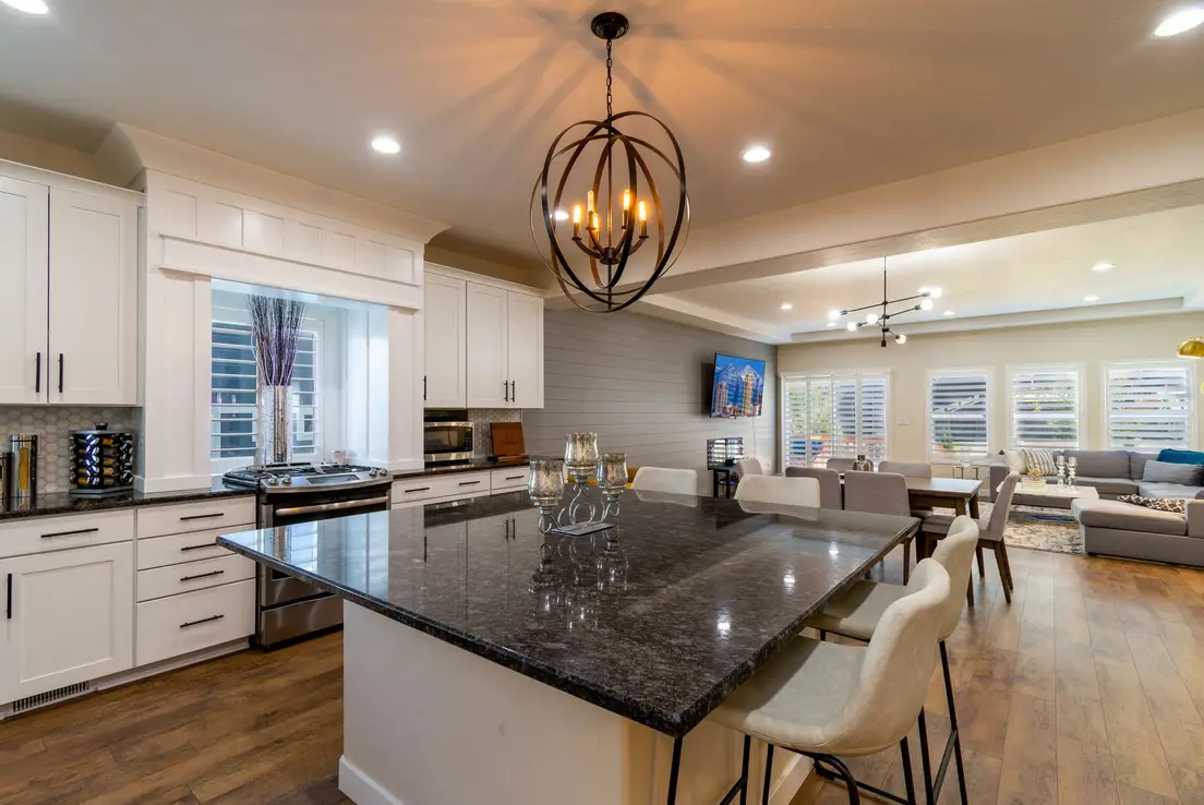 A dark kitchen island with counter stools dividing an open kitchen from the living room seating area