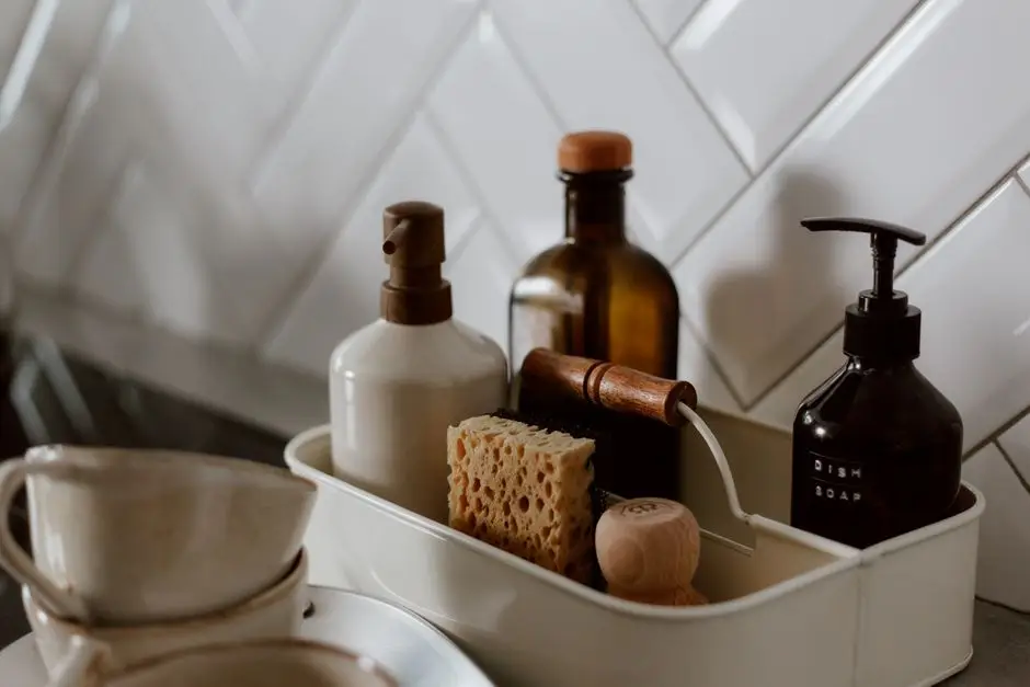 A kitchen sink caddy holding a sponge, dish soap, and cleaning brush against subway tile