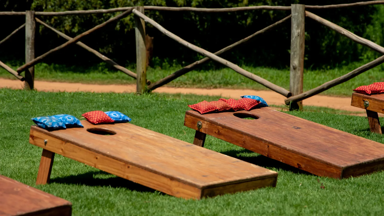 Two wooden cornhole boards with bean bags set up on a lawn for a backyard party