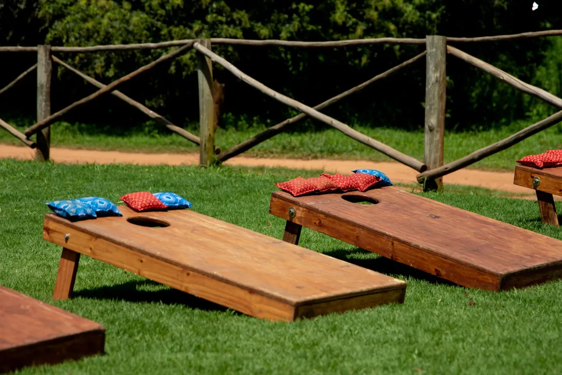 Two wooden cornhole boards with bean bags set up on a lawn for a backyard party