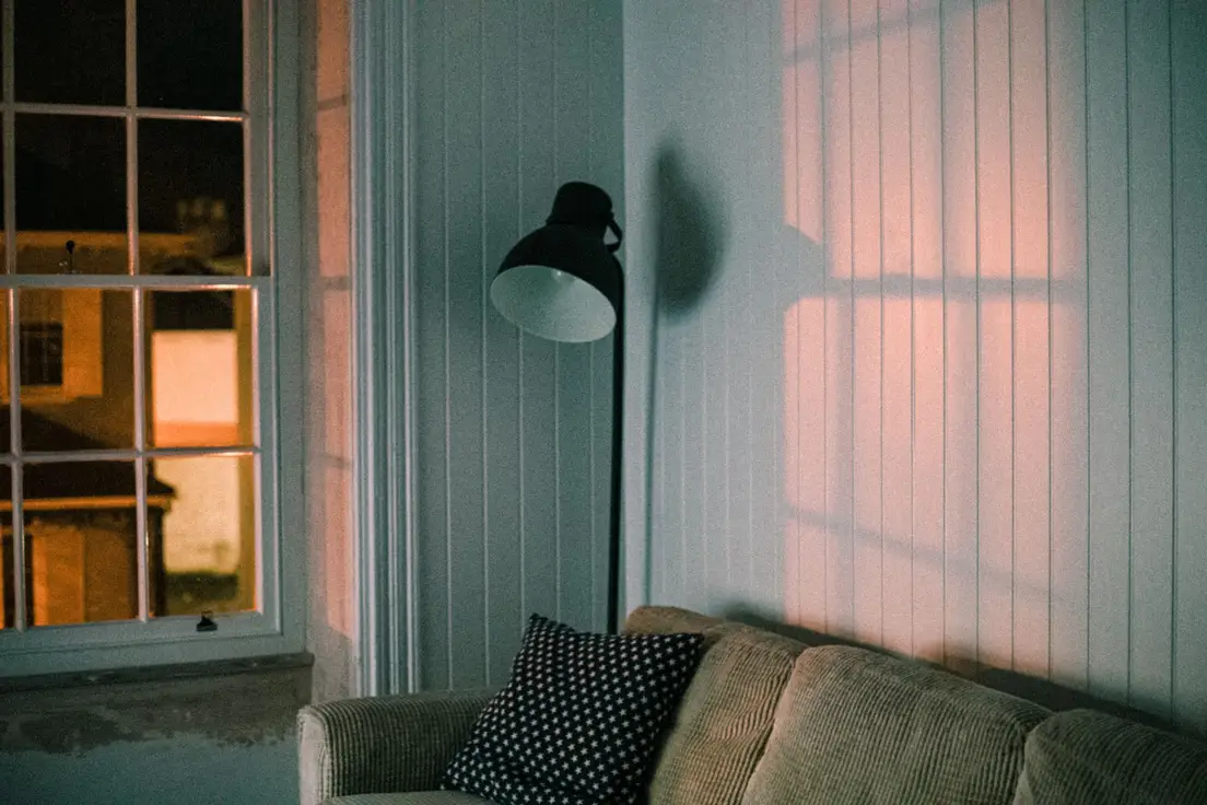 A black floor lamp beside a couch, layering warm lighting in a small apartment living room
