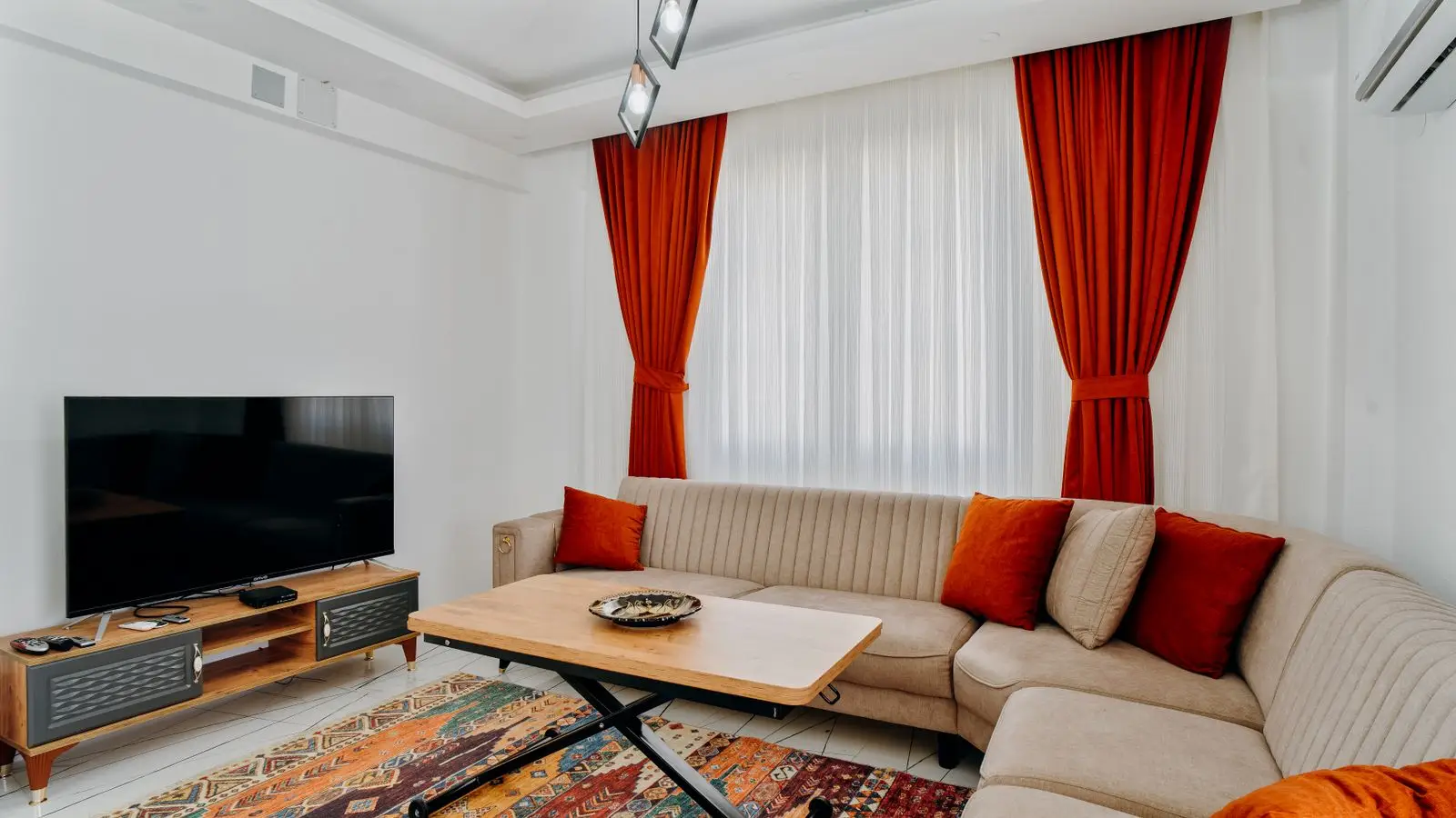 A lift-top coffee table raised to desk height in front of a sectional in a small apartment living room
