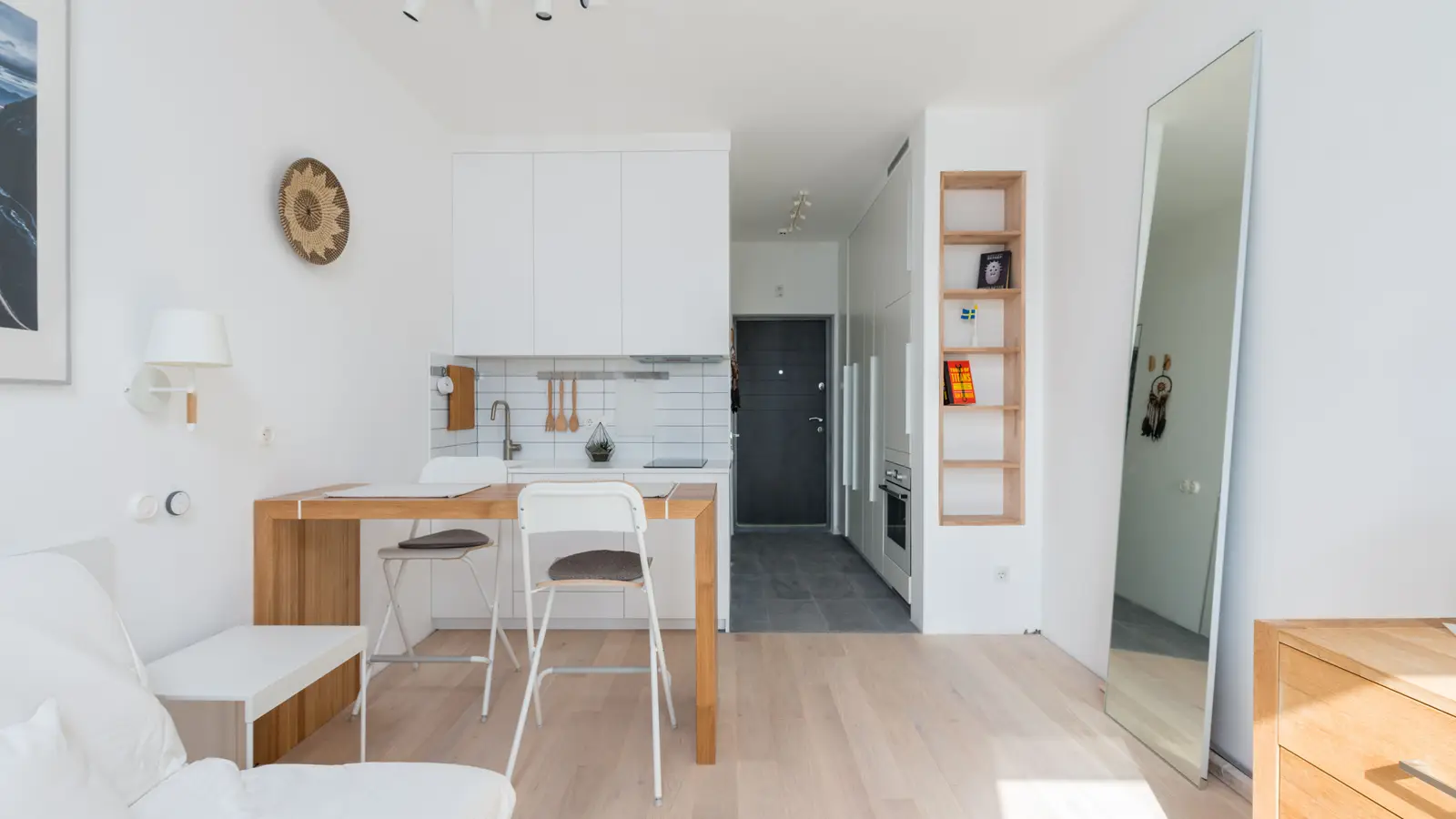 A light, cohesive white and wood color palette in a small apartment studio, making the space feel taller