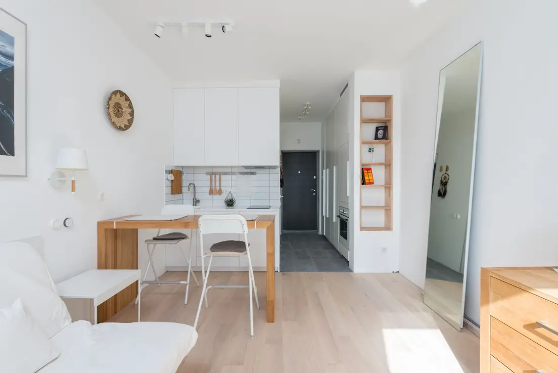A light, cohesive white and wood color palette in a small apartment studio, making the space feel taller