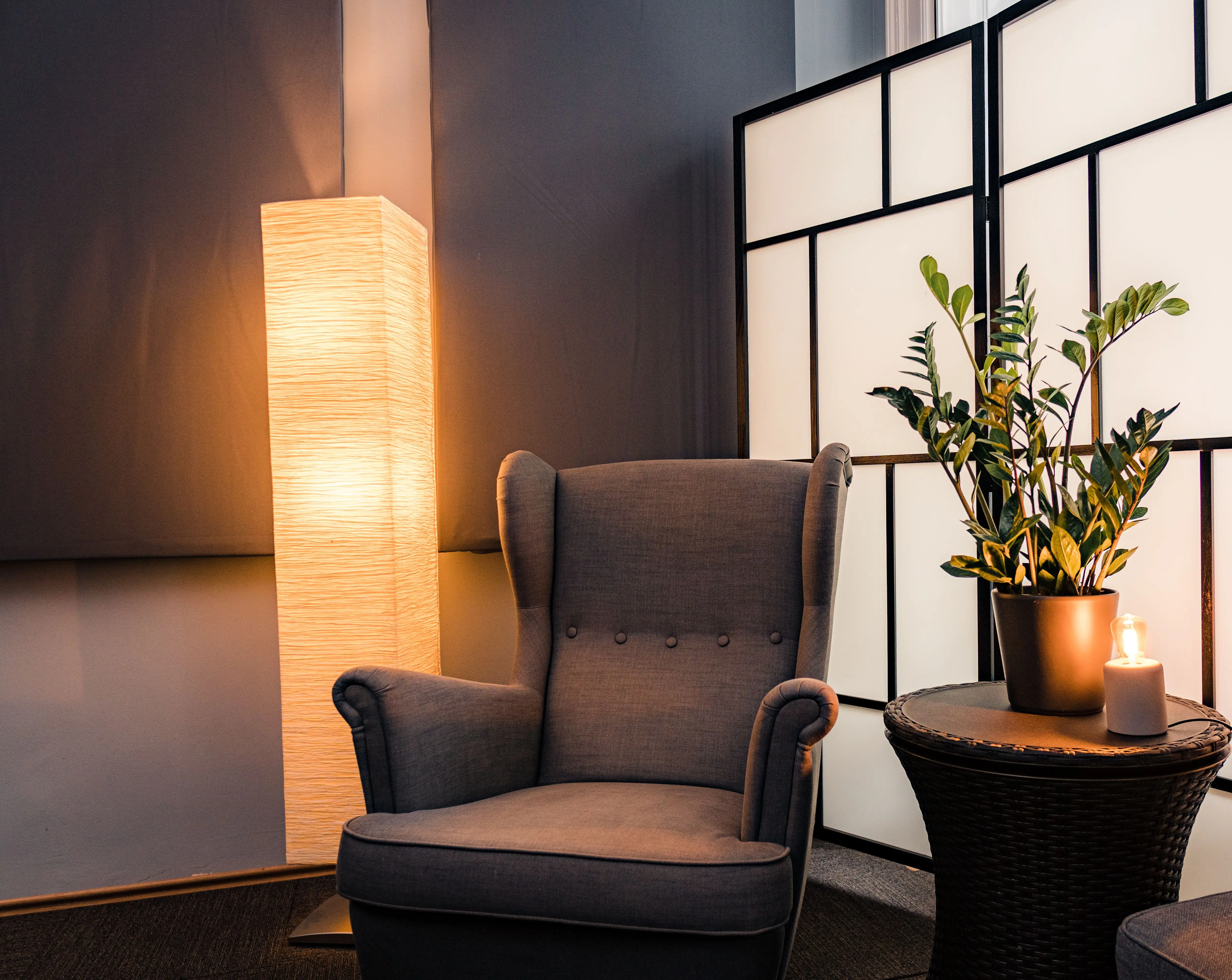 A warm paper-shade floor lamp beside an accent chair in a softly lit living room