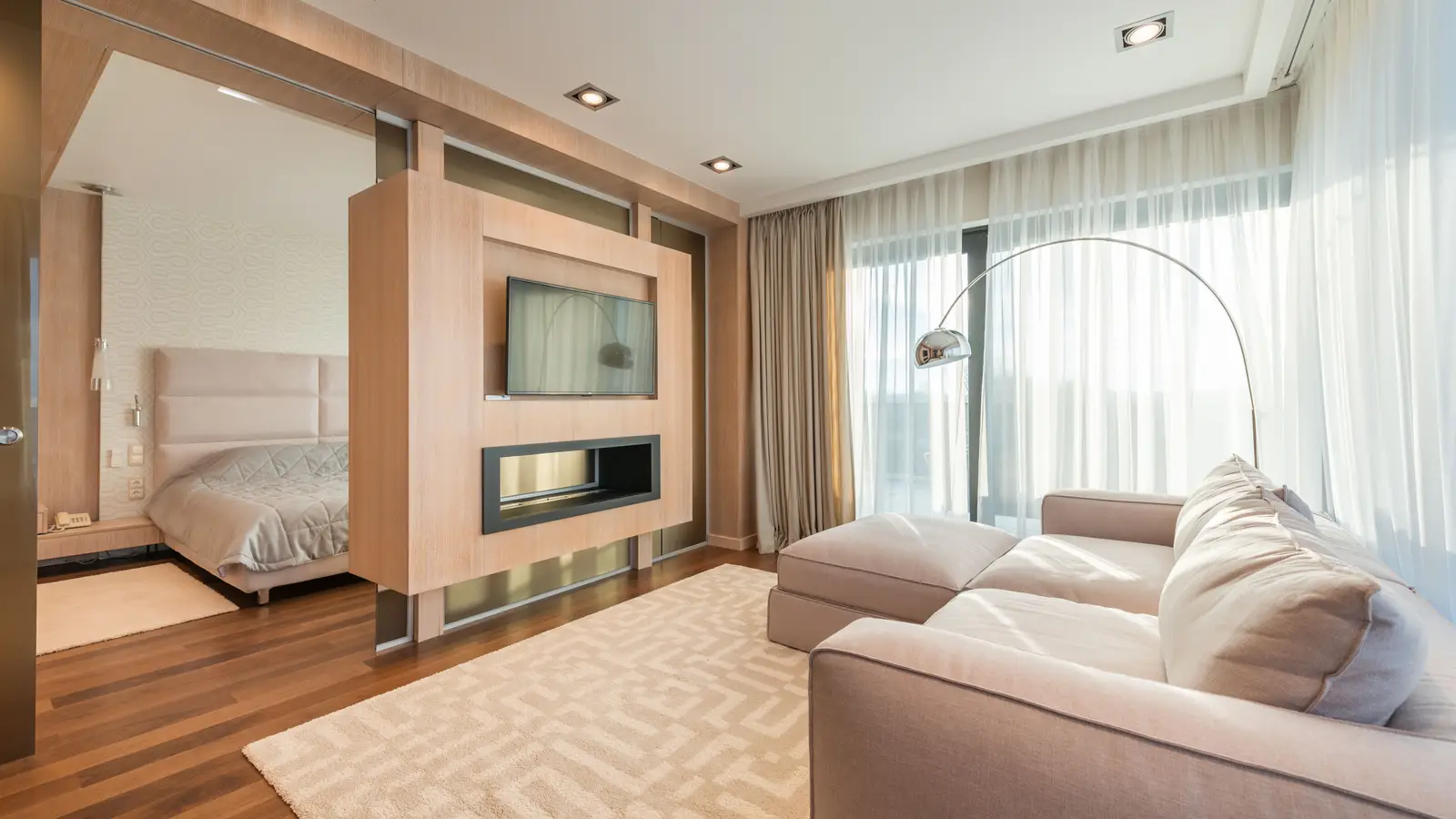 A warm arc floor lamp beside a sectional sofa in a minimalist living room at golden hour