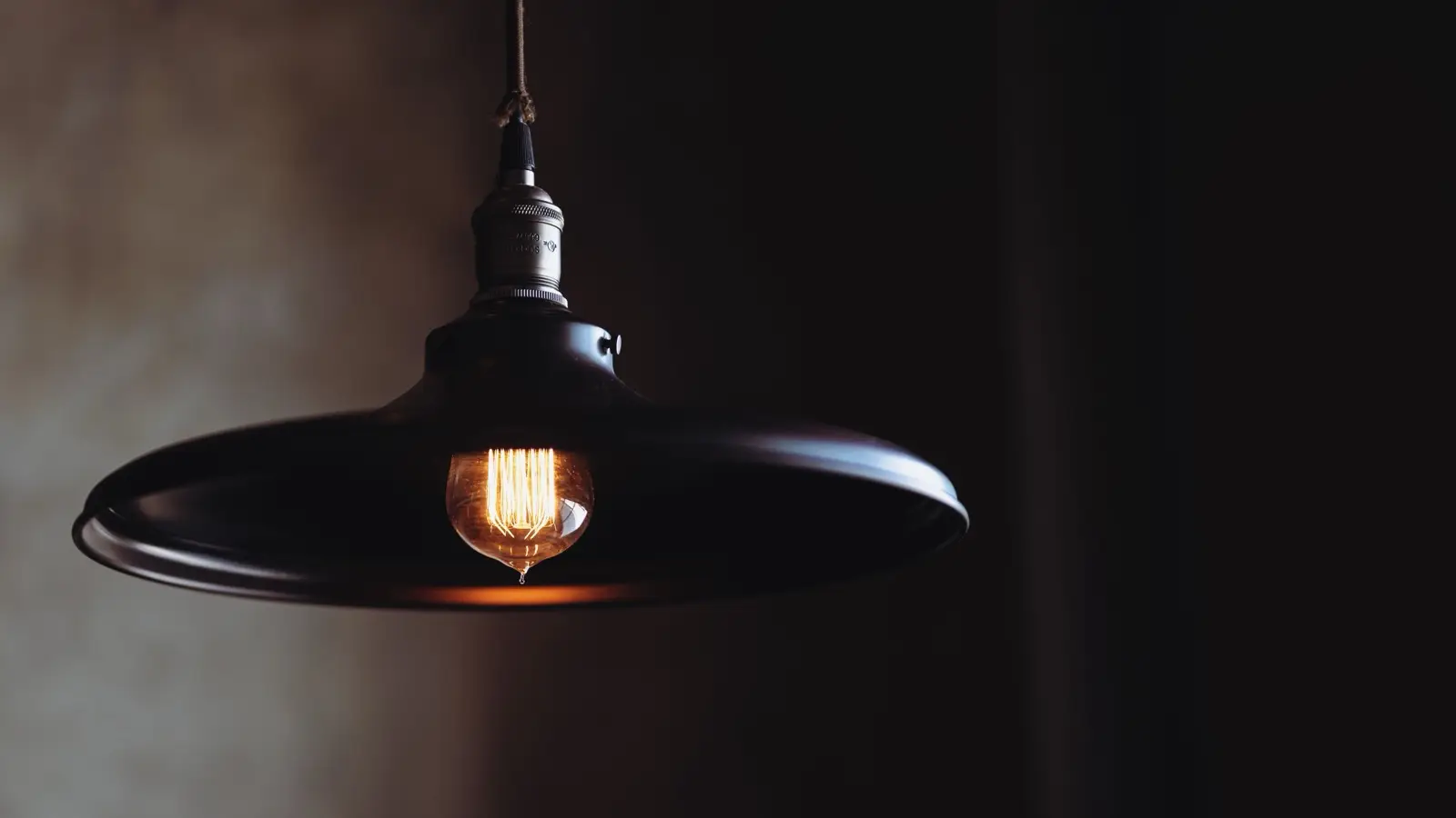 A black industrial-style pendant light fixture with a warm Edison bulb