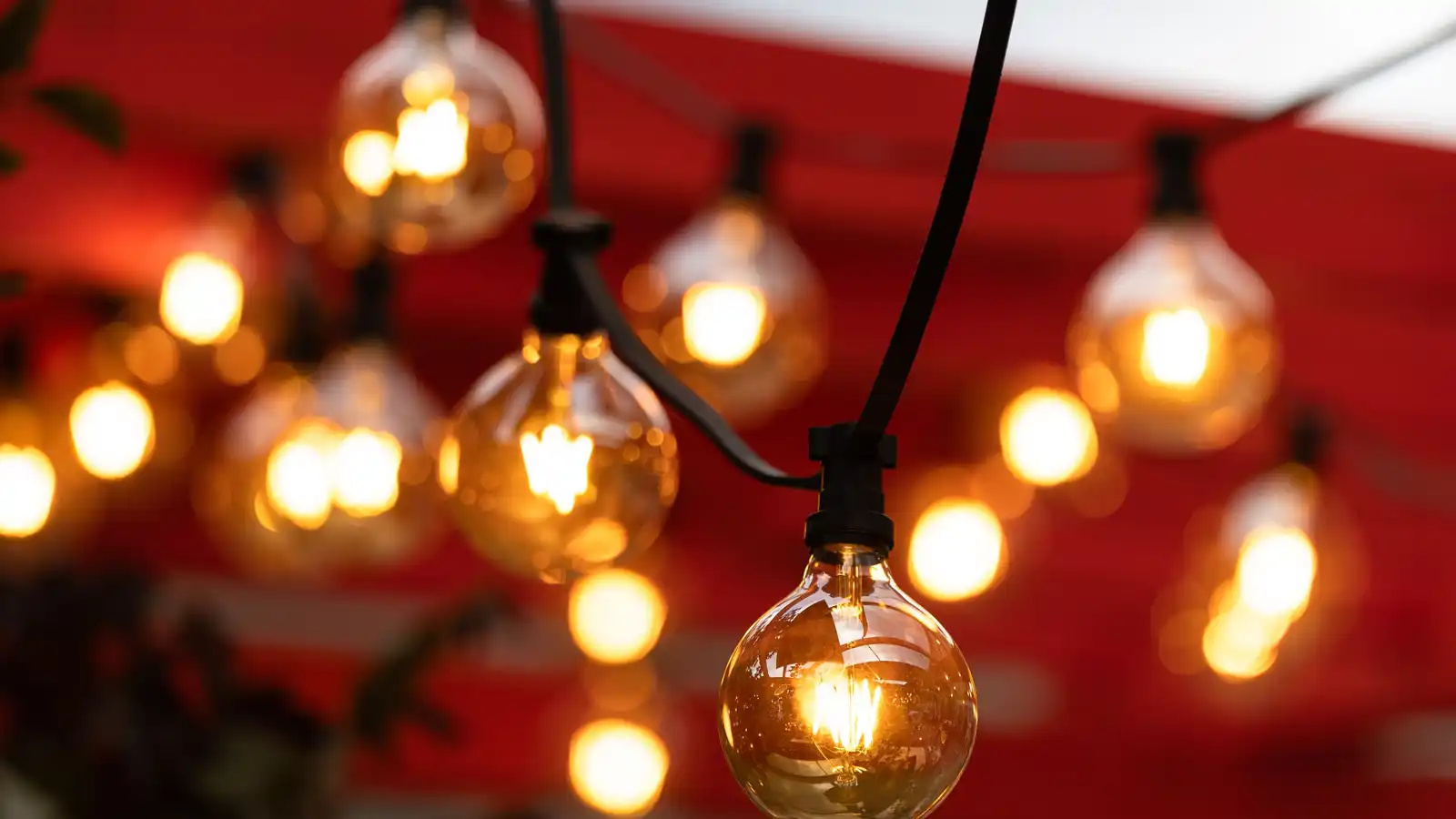 Warm string lights hanging from the beam of a patio cover structure