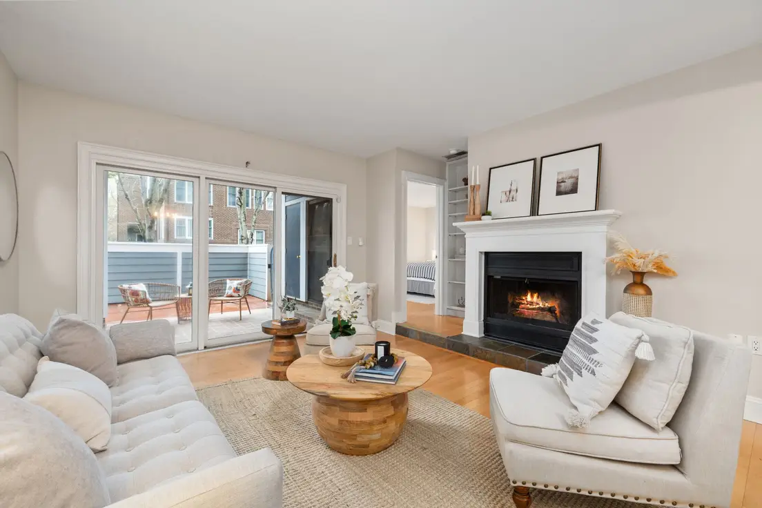 A warm neutral living room with a linen sectional, jute rug, wood coffee table, and a working fireplace