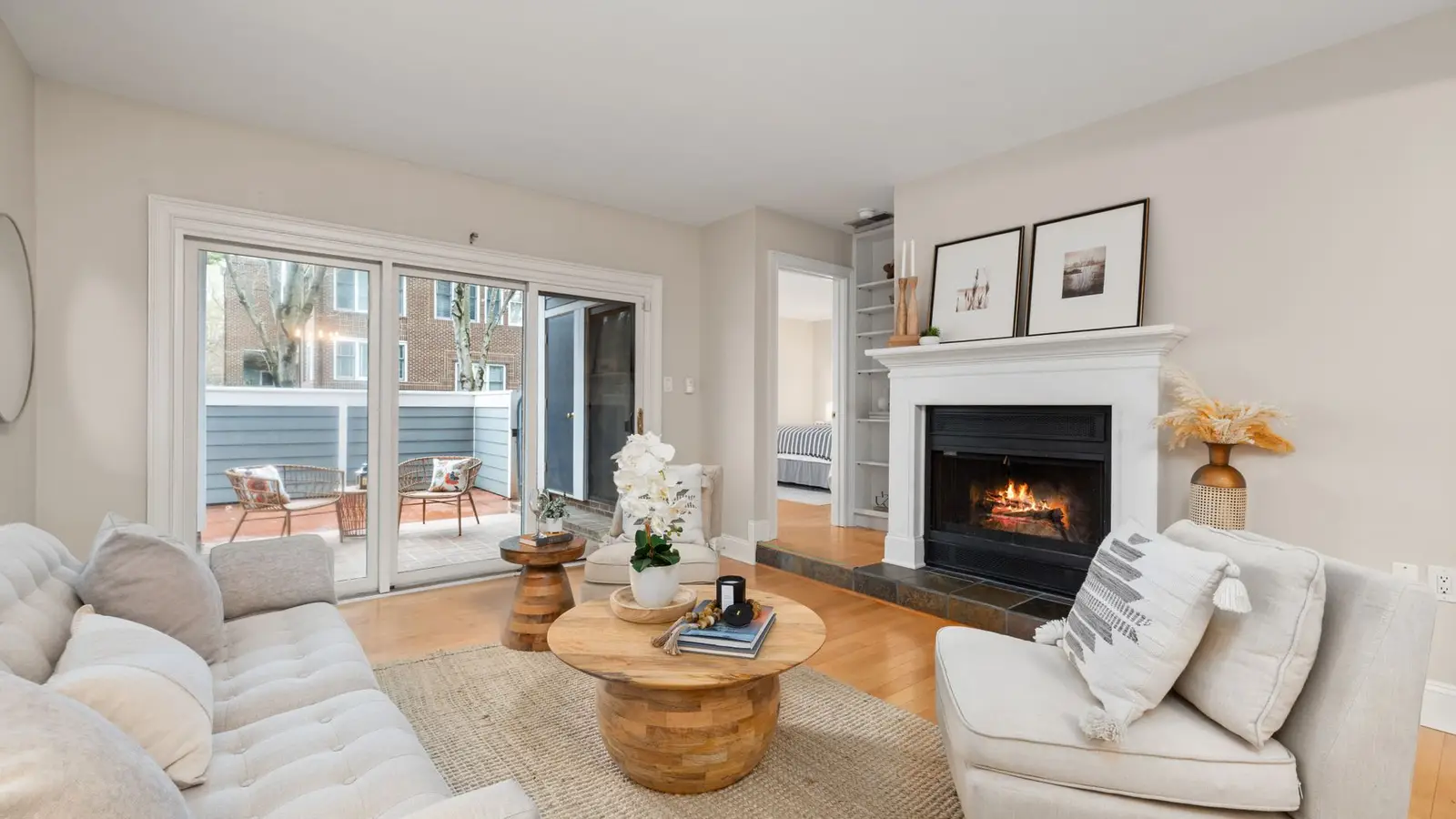 A warm neutral living room with a linen sectional, jute rug, wood coffee table, and a working fireplace