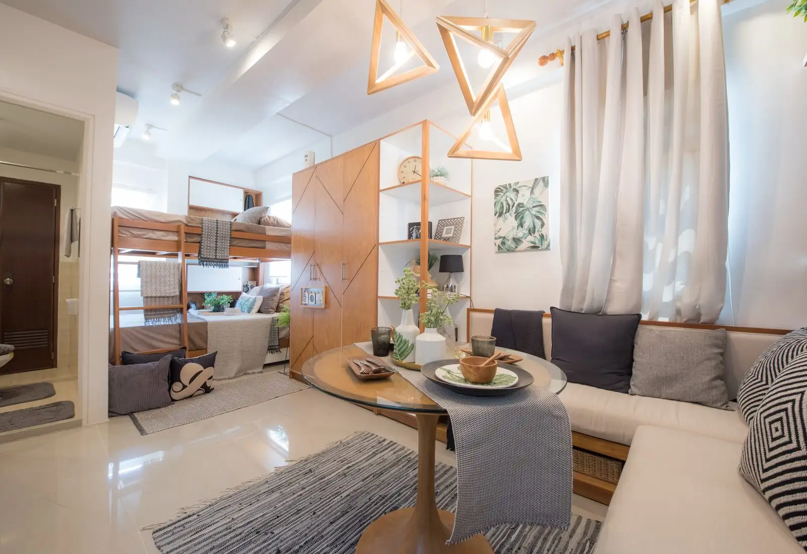 A wooden loft bed above a seating and dining area in a small studio apartment, multifunctional furniture that frees the floor below